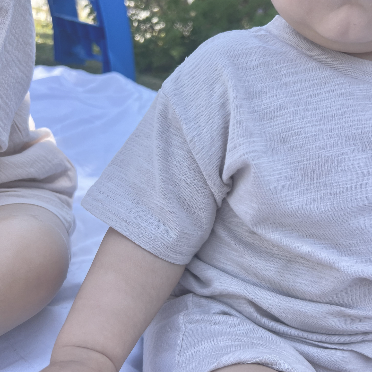 Close-up of a child wearing a light gray shirt outdoors.